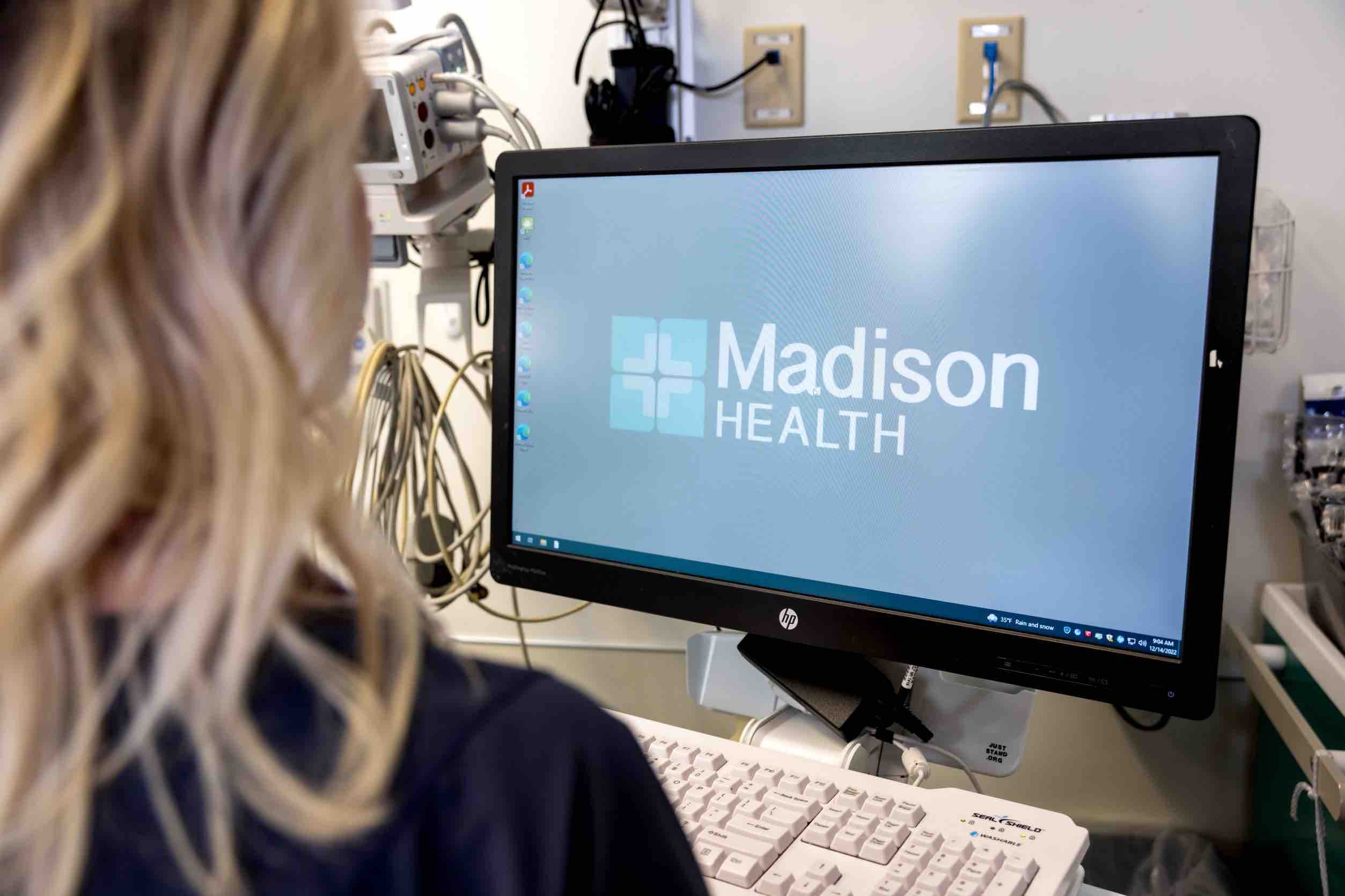 Madison Health Clinician provider looking at computer that has the Madison Health logo on it