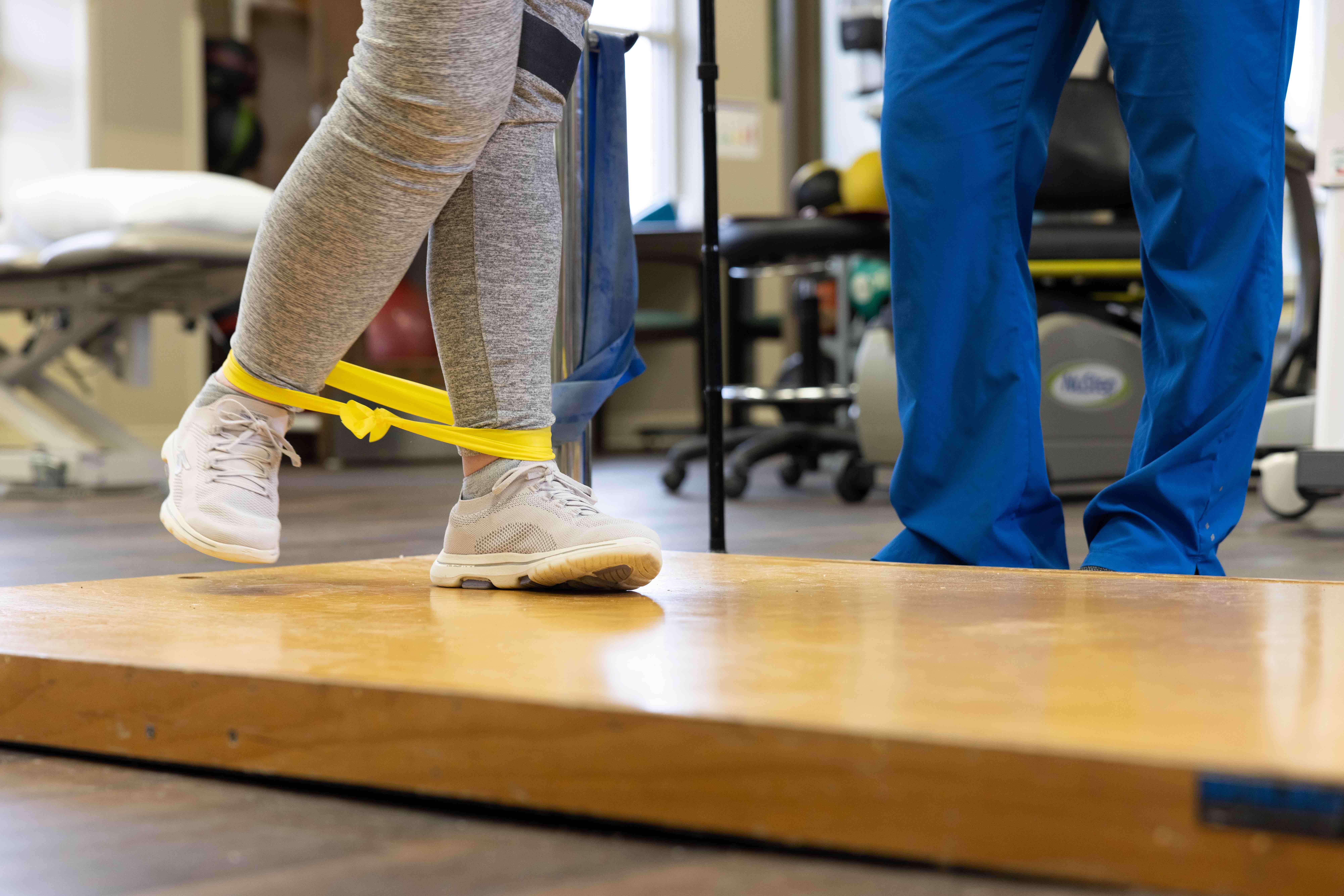 Person walking with band around ankle in physical therapy