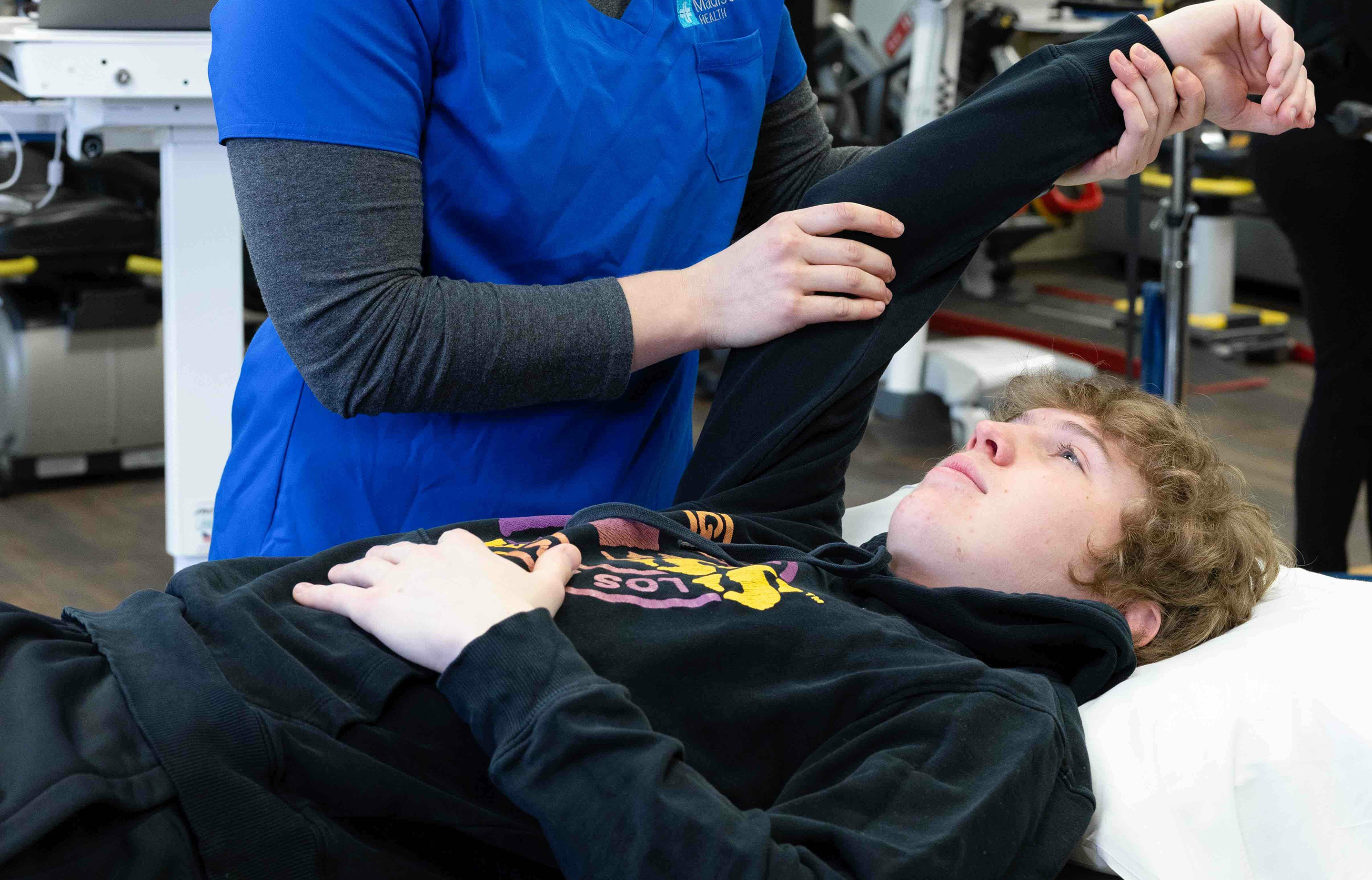 Madison Health Physical Therapy, therapist raising patient's arm while patient is laying down