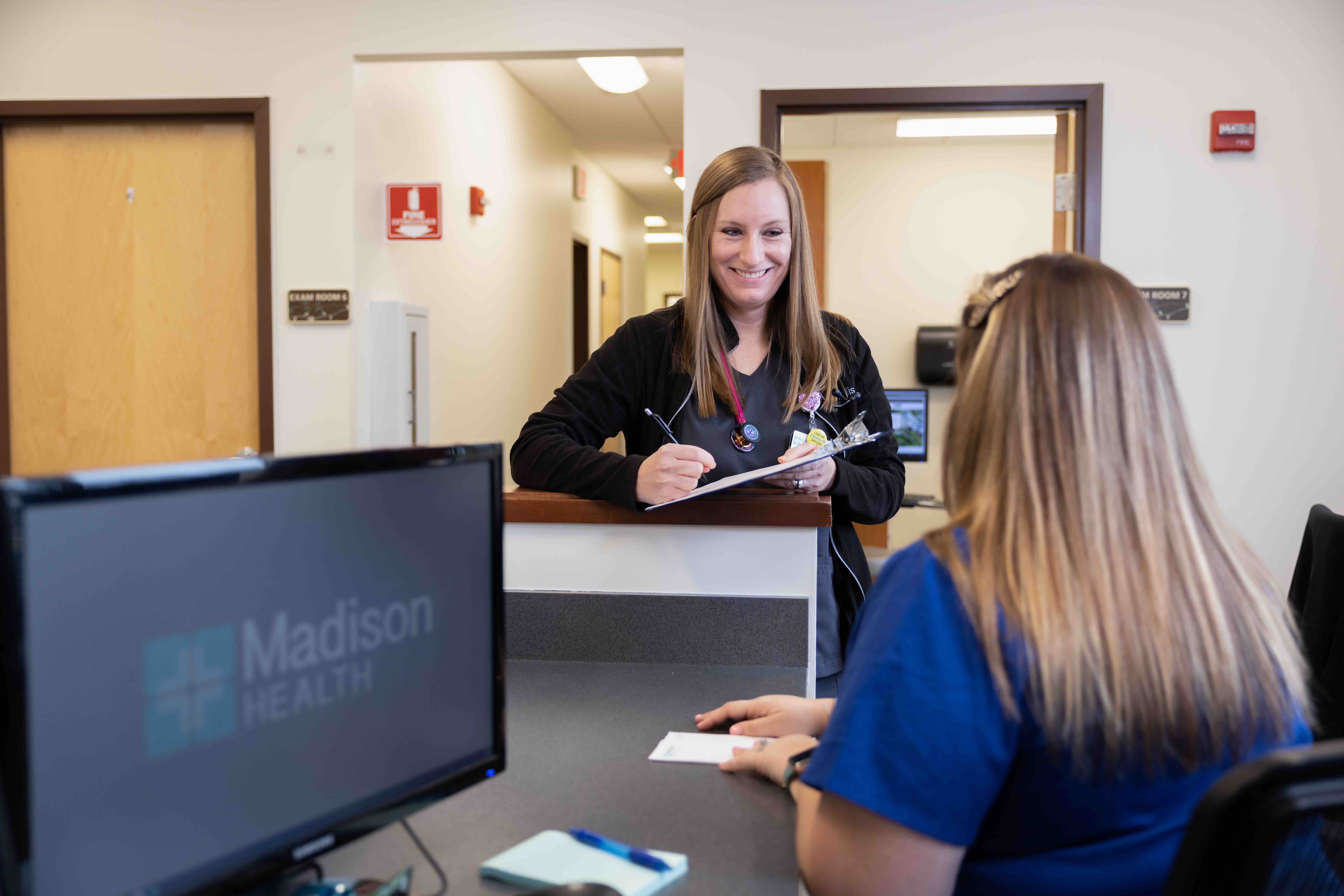 Madison Health Primary Care provider smiling at patient while looking at other provider who has a notepad