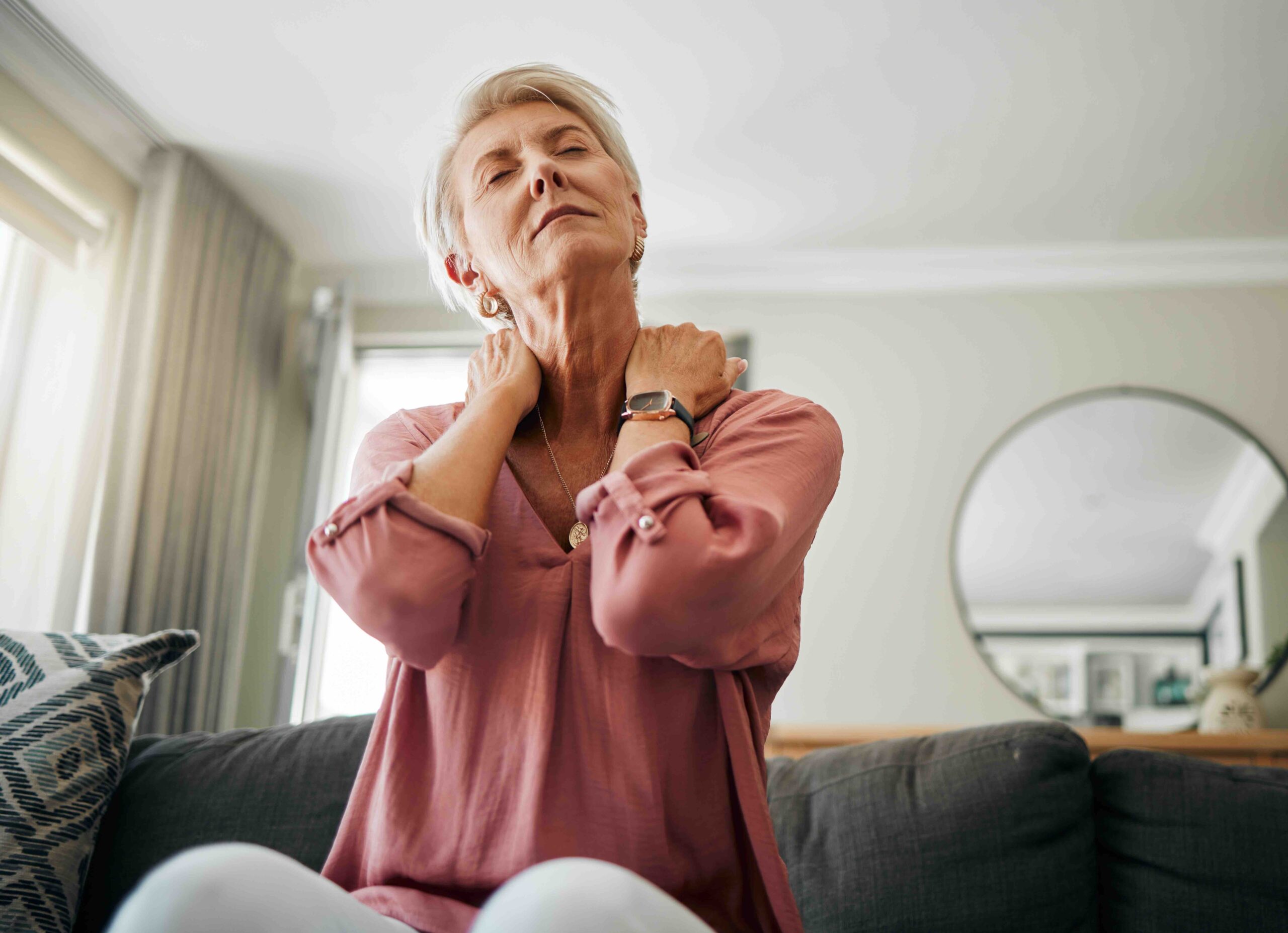 Senior woman with neck pain and stress in living room.